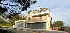 Ein zweigeschossiges Haus mit Balkon, Garagen und einem Berg im Hintergrund.