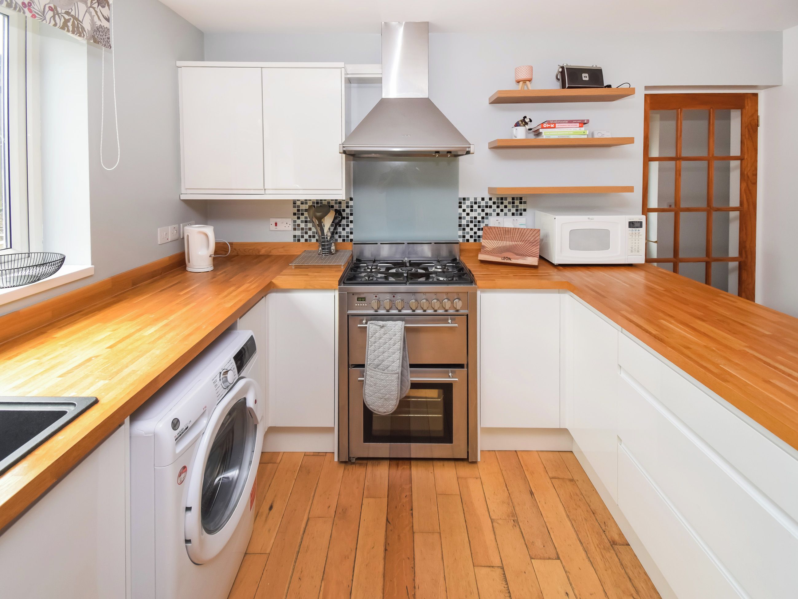 A compact kitchen with a washing machine, a stove, an oven, and a microwave.