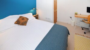 Een slaapkamer met een bed, een bureau, een stoel en een deur.