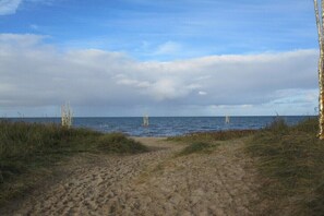 A sandy beach path leading to the sea with sparse vegetation on either side. - Holiday apartment with 2 bedrooms (Cuxhaven)