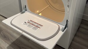 Een voorlader wasmachine van Whirlpool met een bedieningspaneel, een deur met een label en een houten vloer.