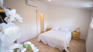 Een slaapkamer met een bed, nachtkastjes, een airconditioning en een deur.