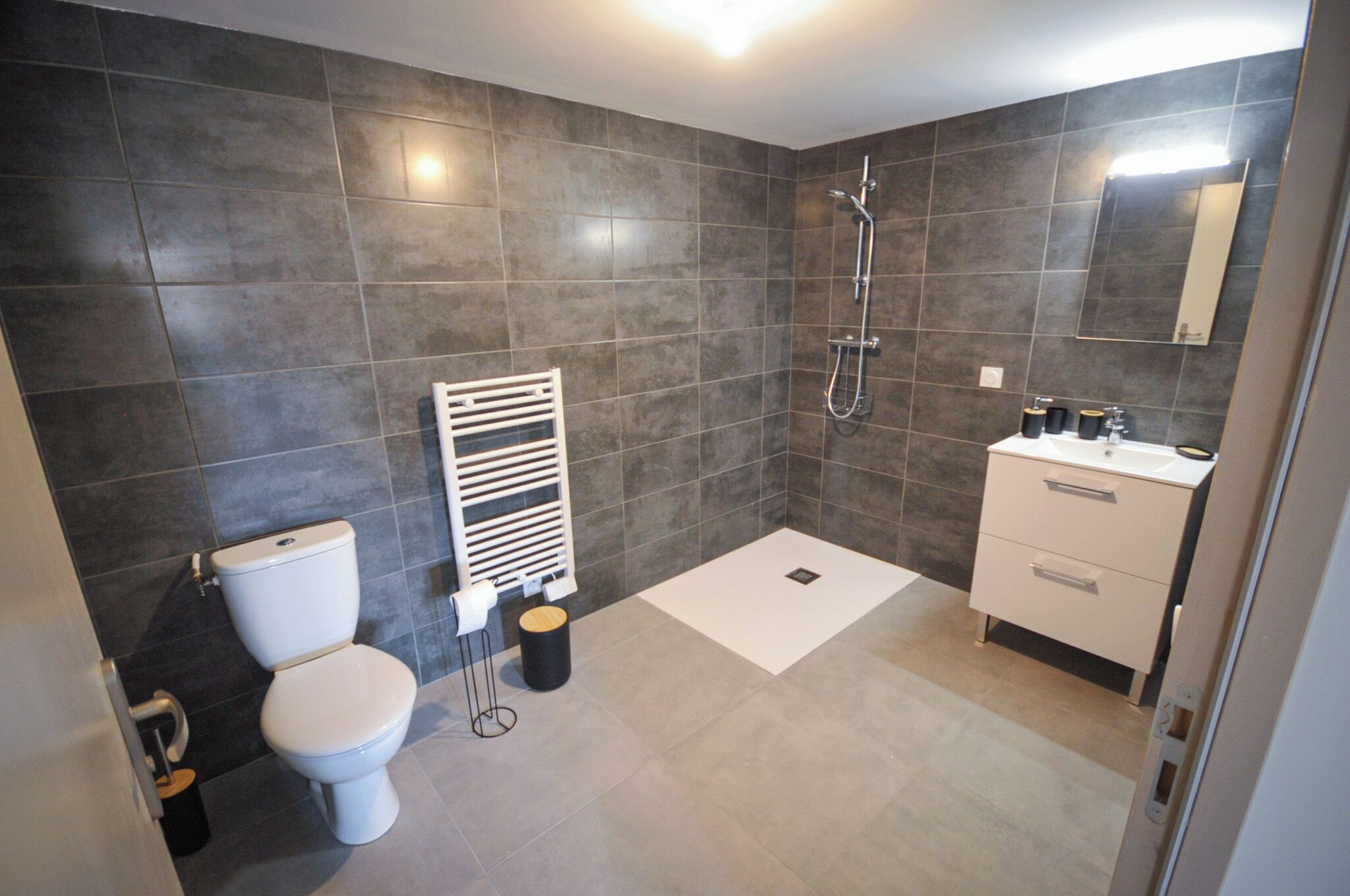 Een moderne badkamer met toilet, douche en wastafel.