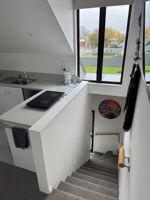 A modern kitchen with a window, a kettle, a sink, and a towel rack.
