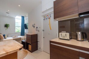 Eine moderne Küche mit Toaster, Wasserkocher und Schränken. Es gibt eine kleine Essecke mit Tisch und Stühlen.
