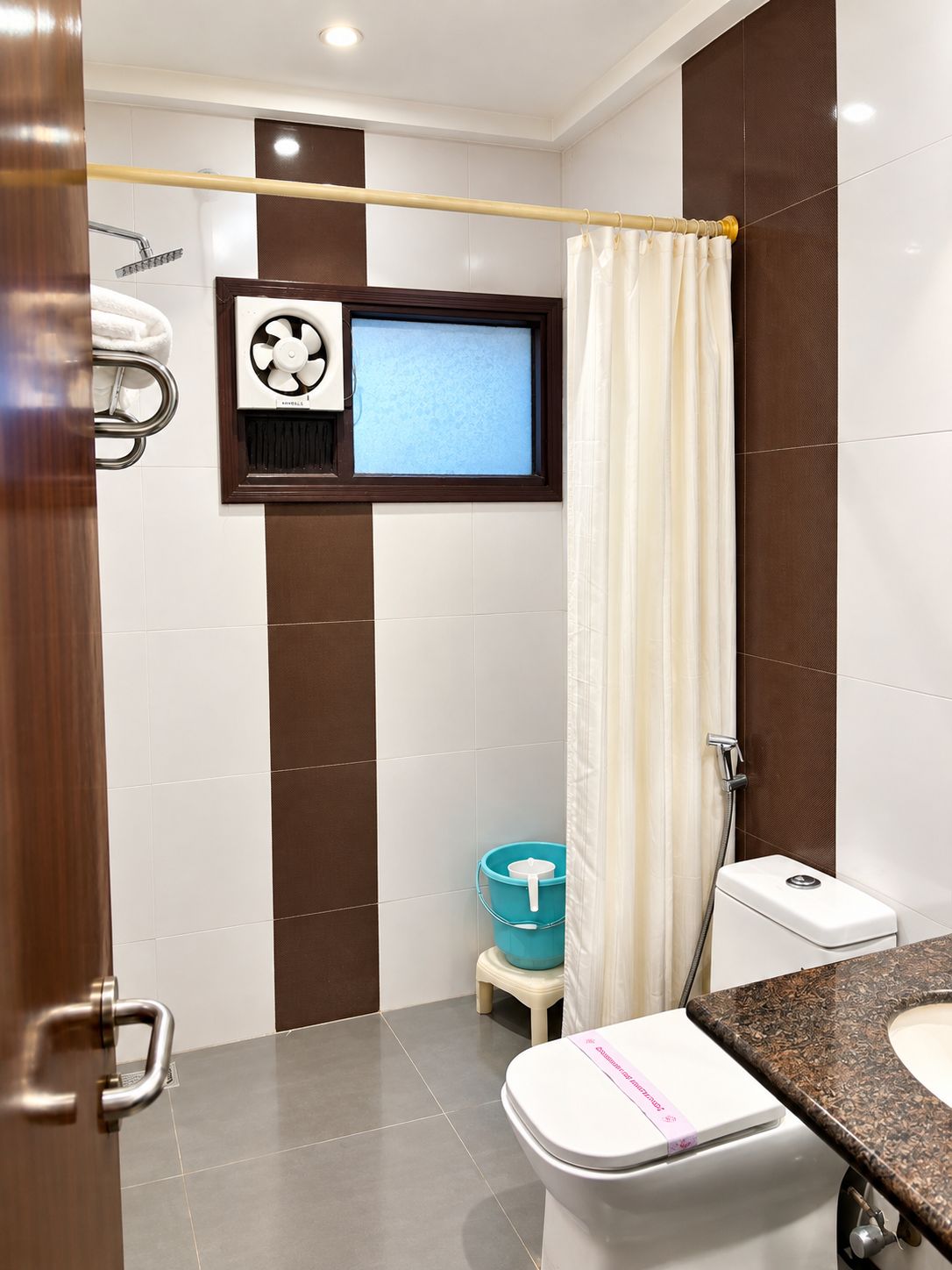 A modern bathroom with a toilet, a shower, and a window.