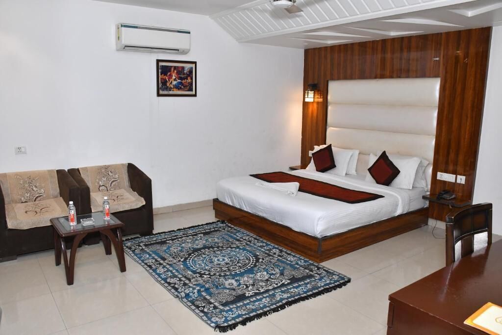 A bedroom with a bed, bedside table, nightstand, and a sofa.
