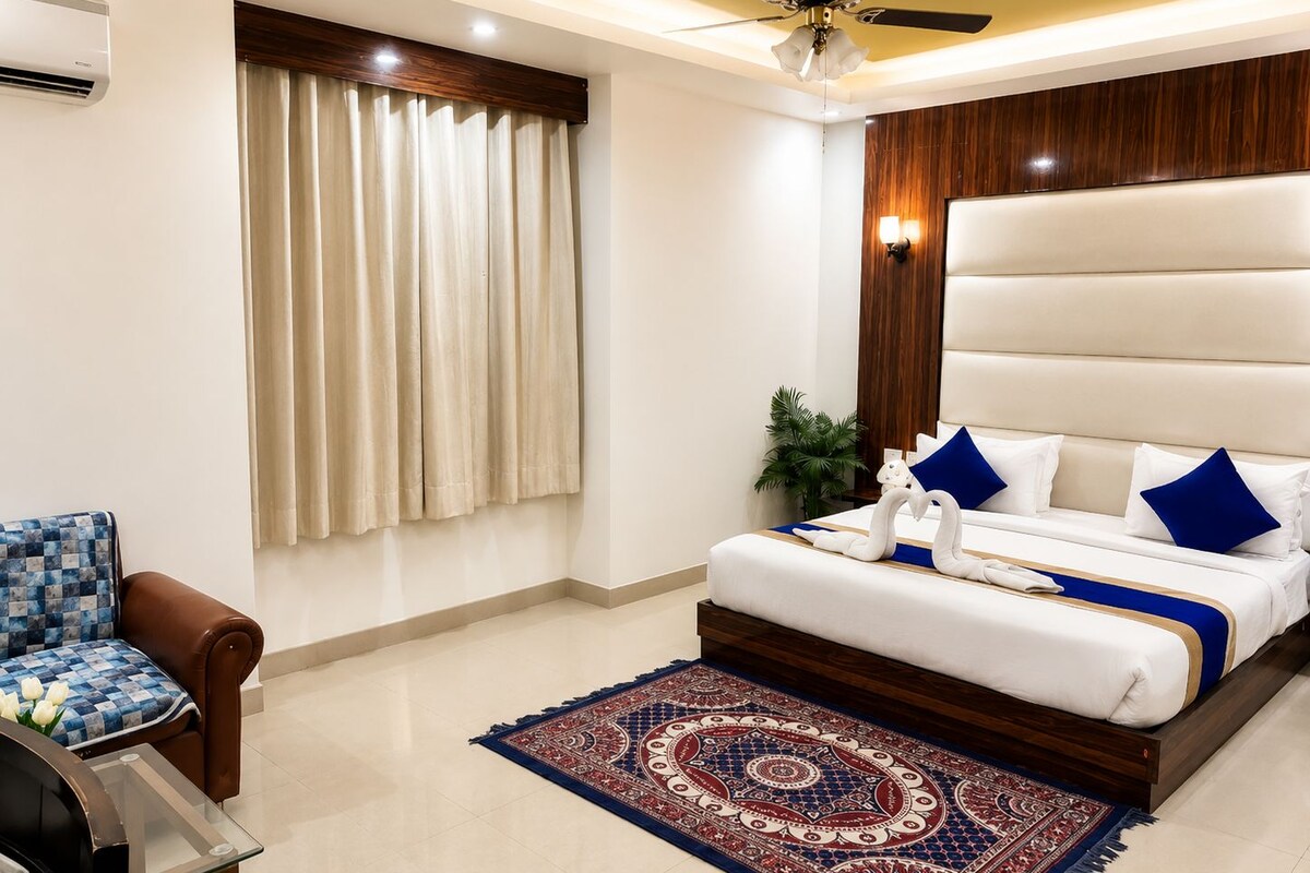 A hotel room with a bed, a chair, a desk, a ceiling fan, and a window with curtains.