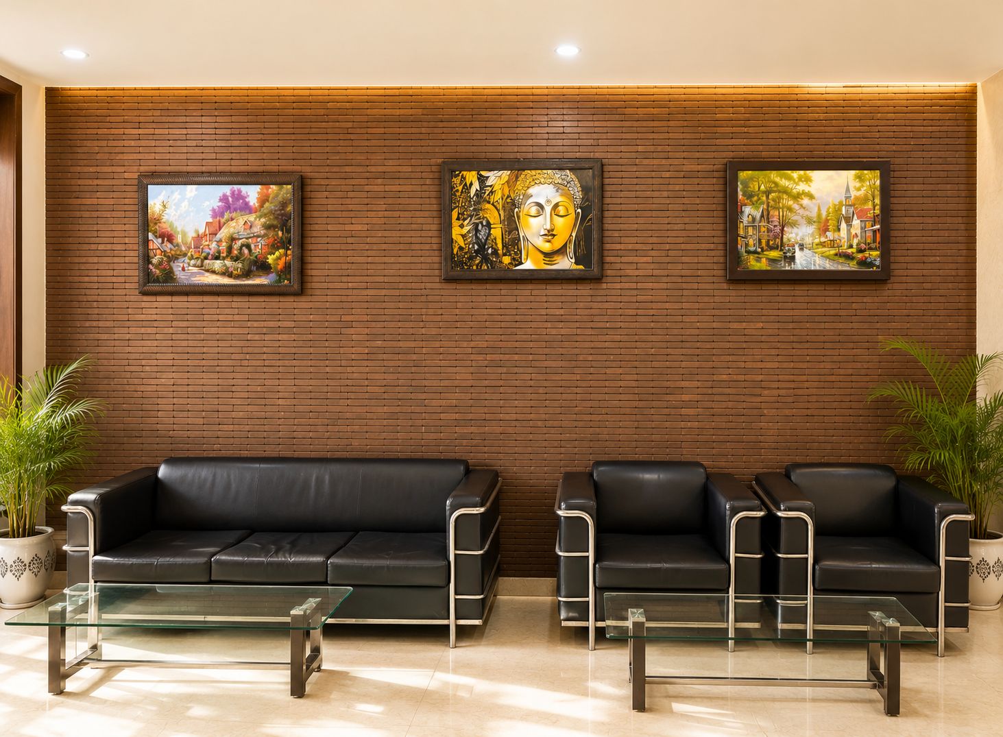 A lobby with two black leather sofas, a glass coffee table, and three framed paintings on a brick wall.