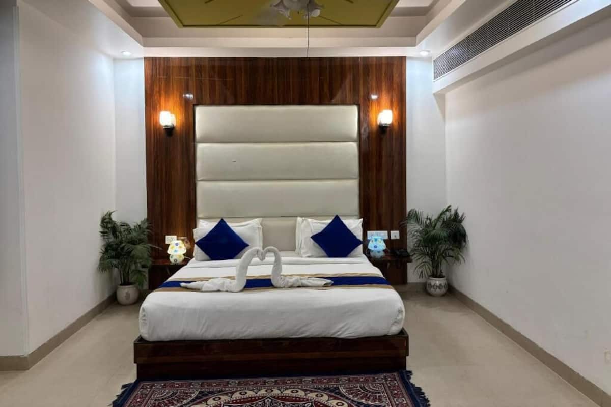 A bedroom with a large bed, a ceiling fan, and two wall-mounted lights.