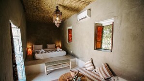 Una habitación con cama, un banco, una mesa con una cesta y un farol colgante.