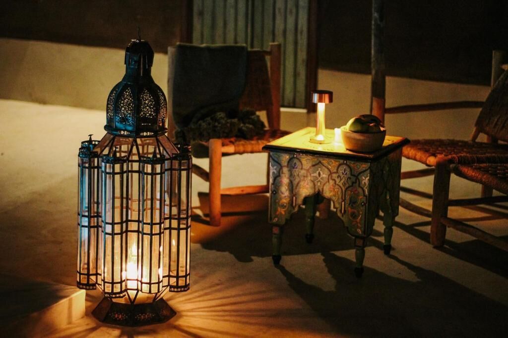 A traditional lantern, a small table with a candle, and a chair in a dimly lit room.