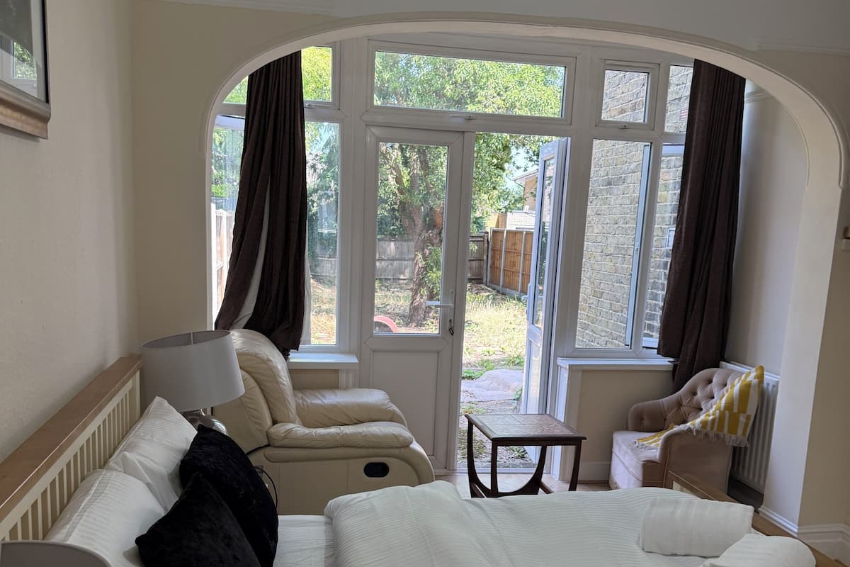 Quarto de hotel com cama, uma cadeira, uma mesa e vista para o exterior.