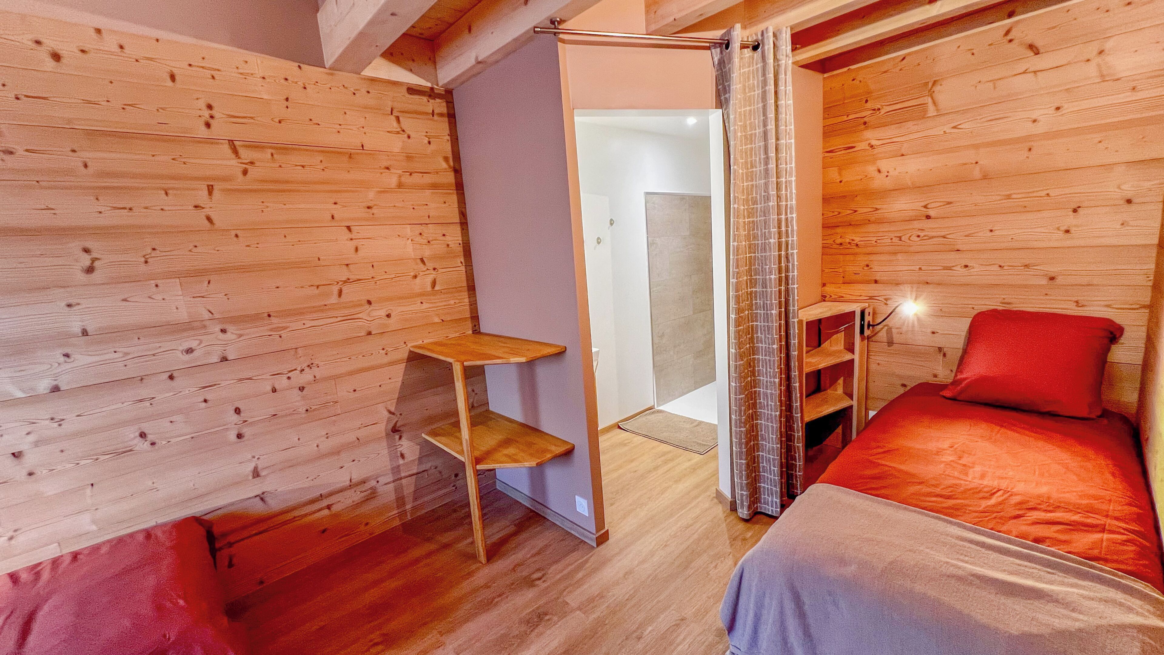 Un intérieur en bois comprenant un lit, une petite étagère et un espace douche.