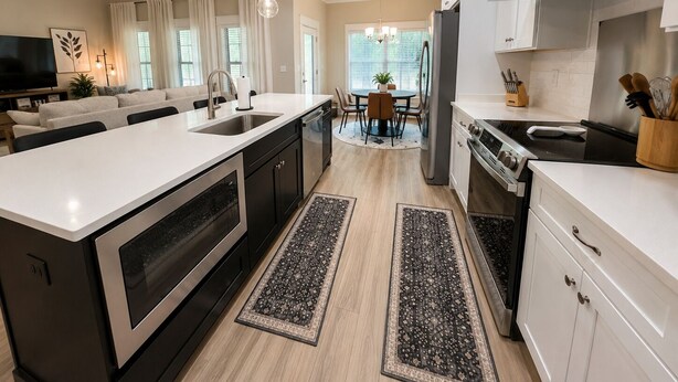A modern kitchen with a central island, stainless steel appliances, and a dining area with a round table.