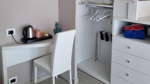 A compact room with a white desk, chair, and shelving unit.