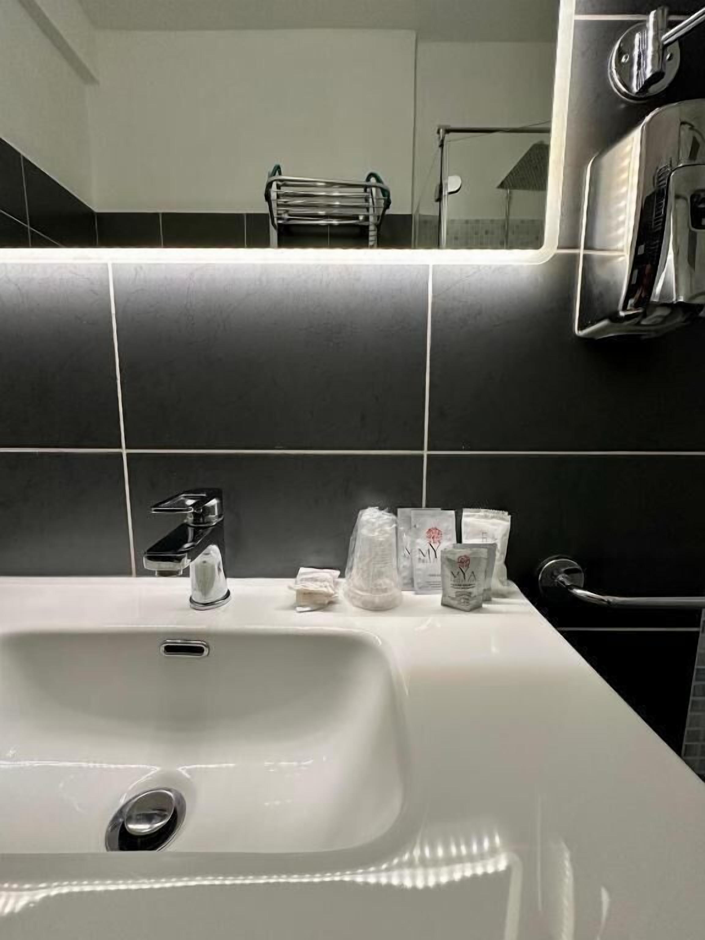 A bathroom with a white sink, a towel rack, and toiletries on the counter.