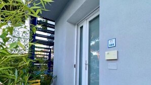 A balcony with a yellow chair, a potted plant, and a door with a sign.