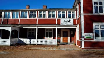Un edificio rojo y blanco con un letrero que dice 'Husby Wardehus' y otro letrero que anuncia 'Restaurante Bar Hotel Galleri'.