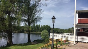 A lakeside view with a wooden deck, a lamp post, and a white fence. - Husby Wardshus (Dala-Husby)