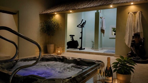 A spa area with a hot tub, exercise equipment, and a bottle of champagne. - Private Spa & Charming Patio (Near Avignon & the Vineyards) (Roquemaure)