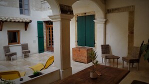 A courtyard with a wooden bench, wicker chairs, a potted plant, and a rustic wooden box. - Private Spa & Charming Patio (Near Avignon & the Vineyards) (Roquemaure)