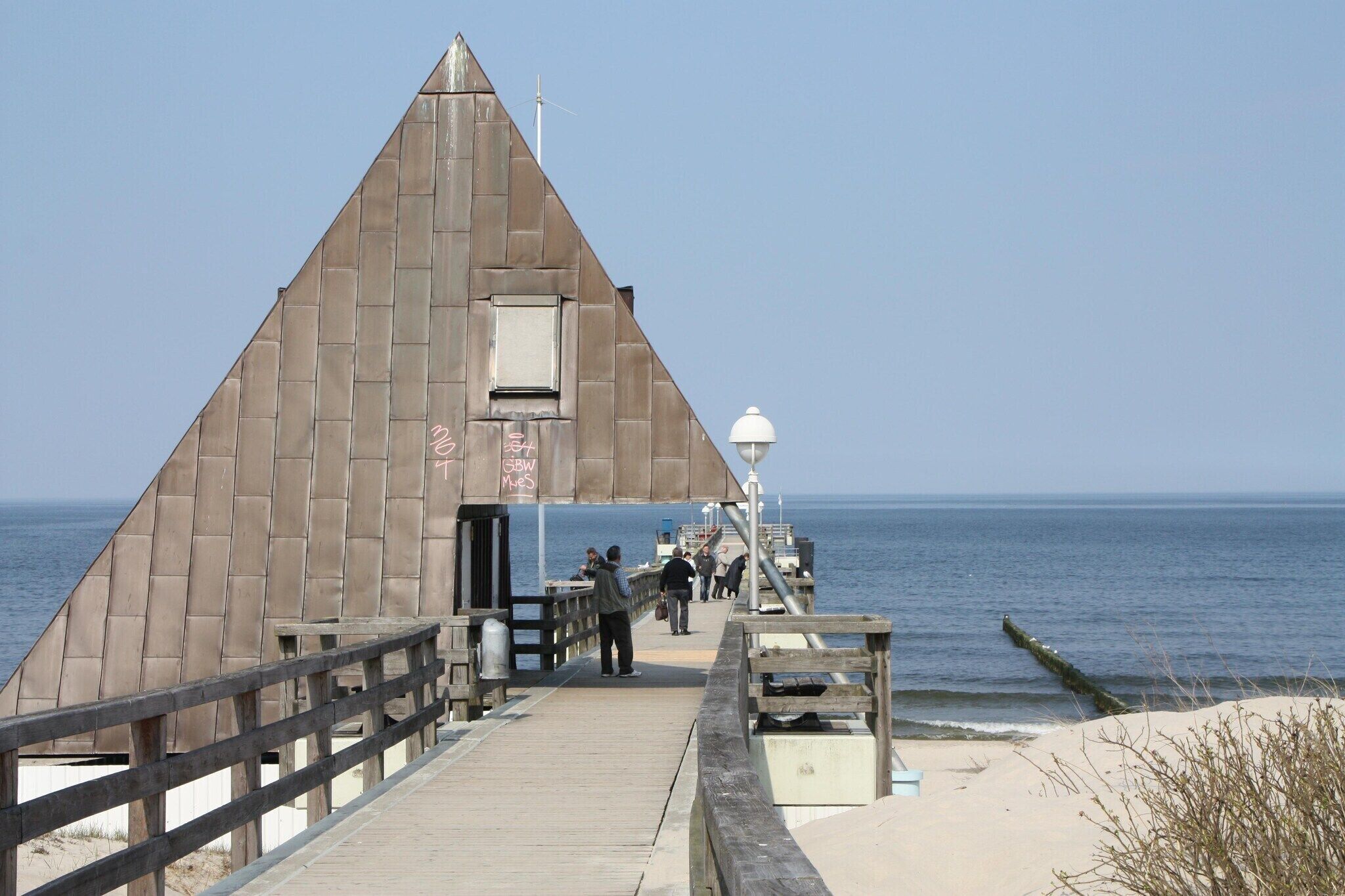 Une jetée menant à un bâtiment triangulaire doté d’une petite fenêtre et d’une enseigne.
