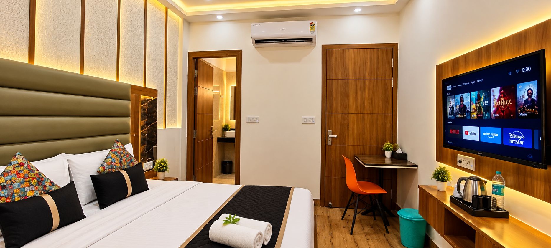 A hotel room with a bed, a desk, a TV, and a bathroom.
