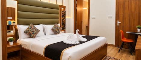 A hotel room with a bed, a desk, a chair, and a small table with a plant.