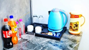 Un taulell de cuina amb una cafetera, tasses, un bullidor i diverses coses per menjar.