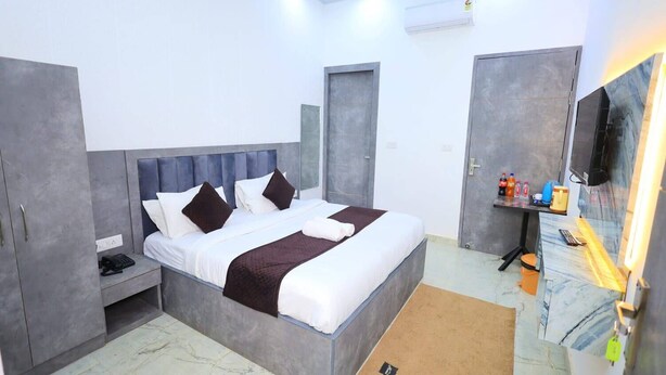 Habitació d'hotel moderna amb llit, armari, escriptori i televisió.