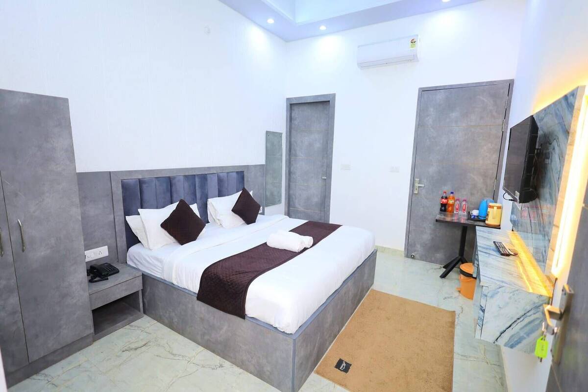 A modern hotel room with a bed, wardrobe, desk, and a television.