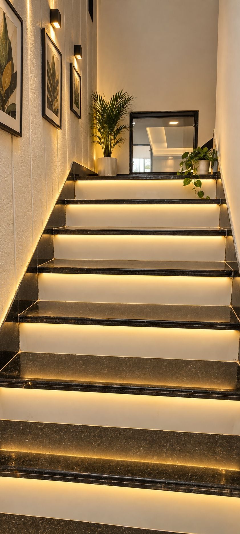 Una escalera con escalones iluminados e impresiones botánicas enmarcadas en las paredes.