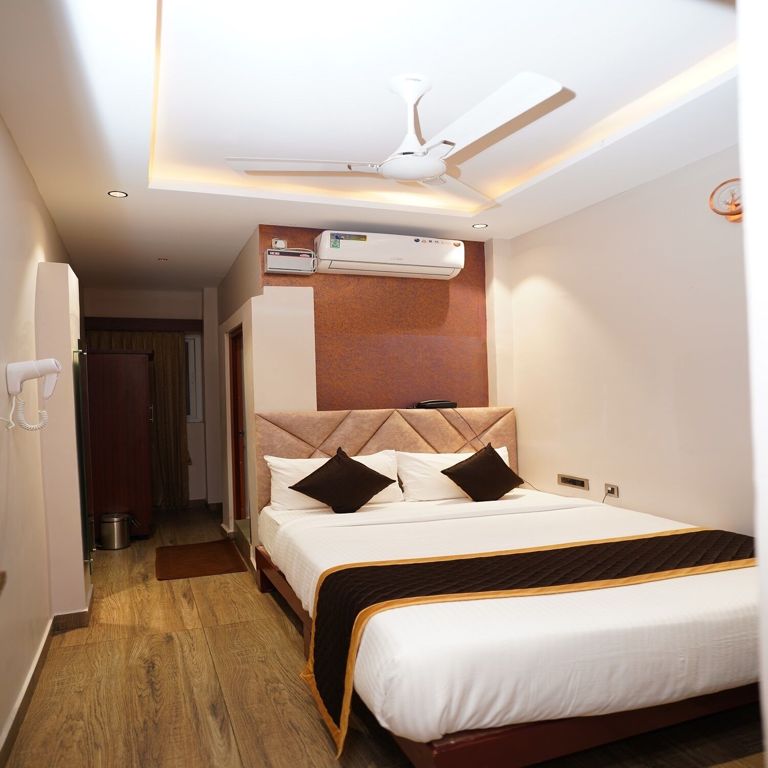 Una habitación de hotel con cama, ventilador de techo, aire acondicionado y teléfono.