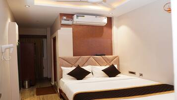 Una habitación de hotel con cama, ventilador de techo, aire acondicionado y teléfono.