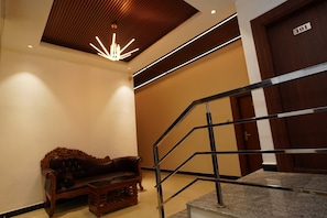 A hotel lobby with a wooden bench, a staircase with metal railings, and a door marked '101'. - G Grand Inn (Thanjavur)
