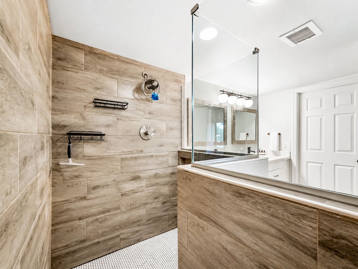 Un baño moderno con pared de madera, un espejo grande y zona de ducha.