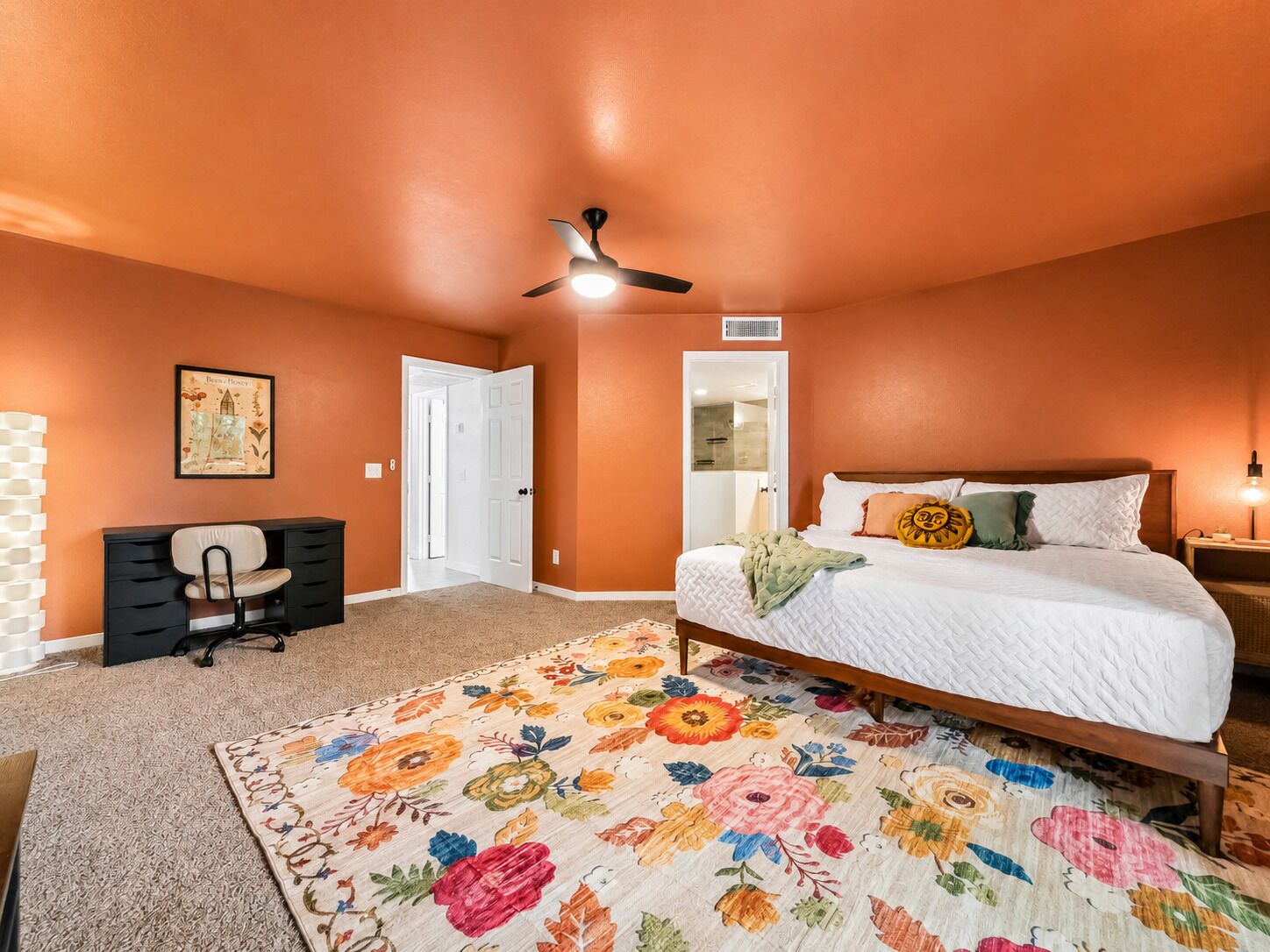 Une chambre à coucher avec un lit, un bureau, une chaise, un ventilateur de plafond et une porte.