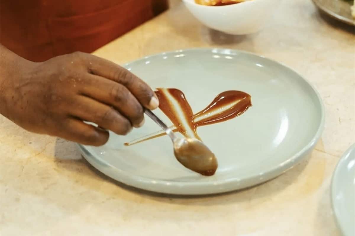 Una persona en una cocina preparando comida, con un tazón de salsa y un plato con salsa sobre una encimera.