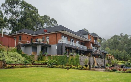 A two-story house with a balcony, surrounded by a well-maintained garden.