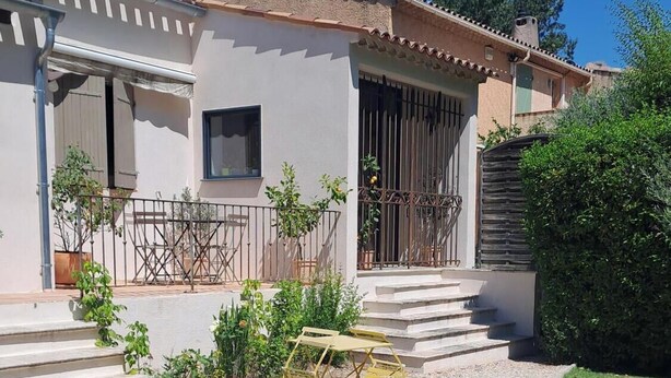 A two-story house with a gravel driveway, a small outdoor seating area, and a staircase leading to the entrance. - HOUSE IN THE AIX COUNTRYSIDE (AIX EN PROVENCE)
