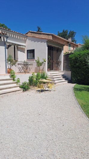 A two-story house with a gravel driveway, a small outdoor seating area, and a staircase leading to the entrance. - HOUSE IN THE AIX COUNTRYSIDE (AIX EN PROVENCE)