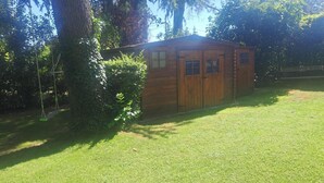 A wooden shed with a door and windows, surrounded by grass and trees. - HOUSE IN THE AIX COUNTRYSIDE (AIX EN PROVENCE)