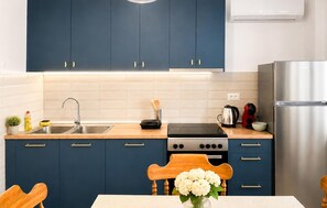 Eine moderne Küche mit dunkelblauen Schränken, einer Edelstahl-Spüle, einem Gasherd und einem Kühlschrank.