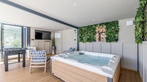 Een moderne kamer met een bubbelbad, een tafelvoetbaltafel en uitzicht op de omgeving.