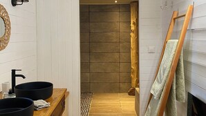 A bathroom with a wooden vanity, two black sinks, a mirror, and a towel rack.