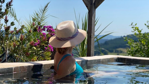 A person in a swimming pool with a view of greenery and hills.