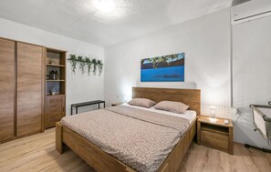 A bedroom with a bed, wooden wardrobe, bedside table, and a painting of a lake. - Gorgeous home in Razvode (Razvode)