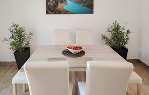 A dining table with a bowl of snacks, two potted plants, and a framed landscape picture on the wall. - Gorgeous home in Razvode (Razvode)