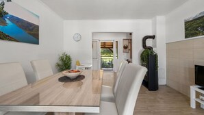 Un comedor moderno con una mesa de madera, sillas blancas y vistas a un jardín a través de un ventanal.